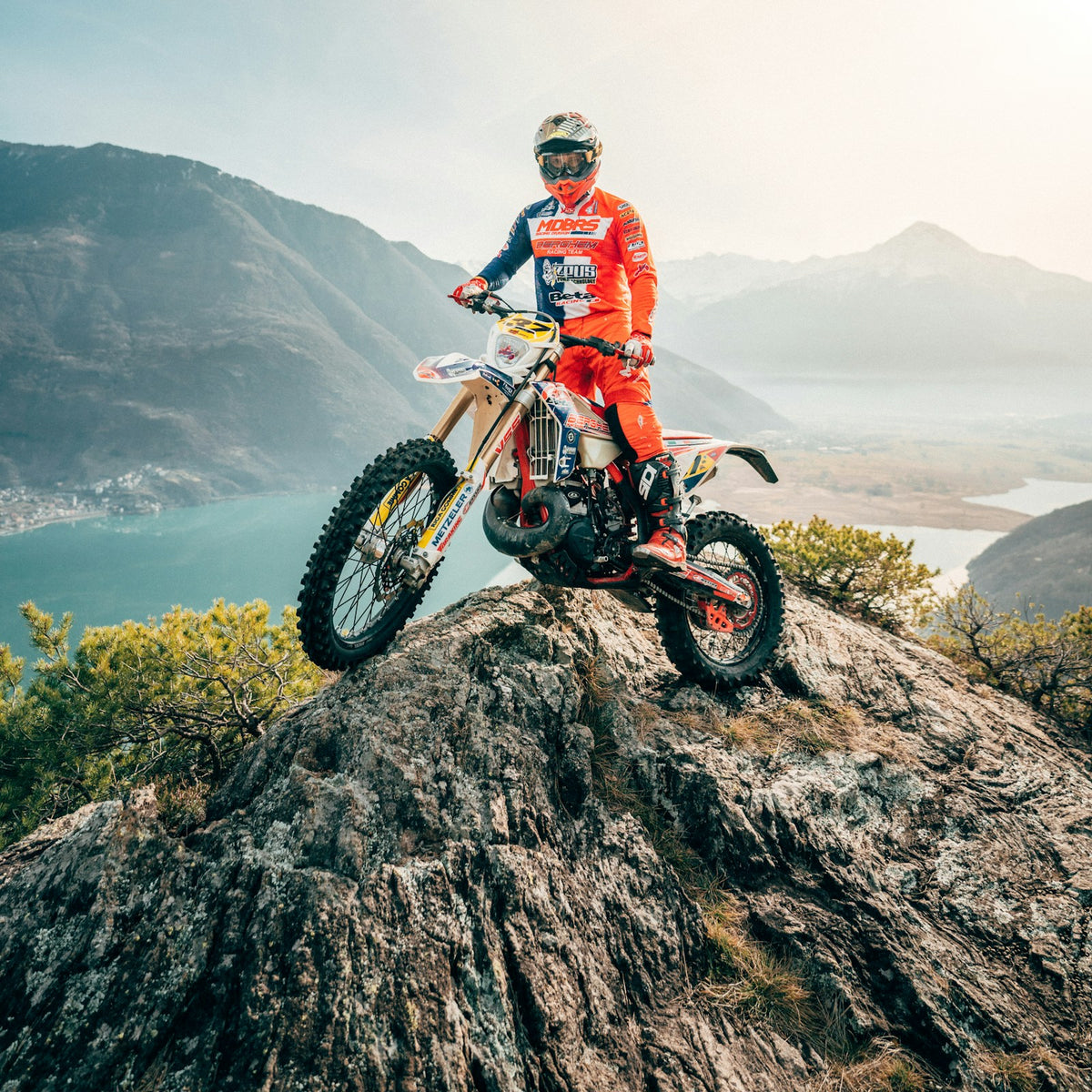 Rider in a red and white off-road suit on a mountain