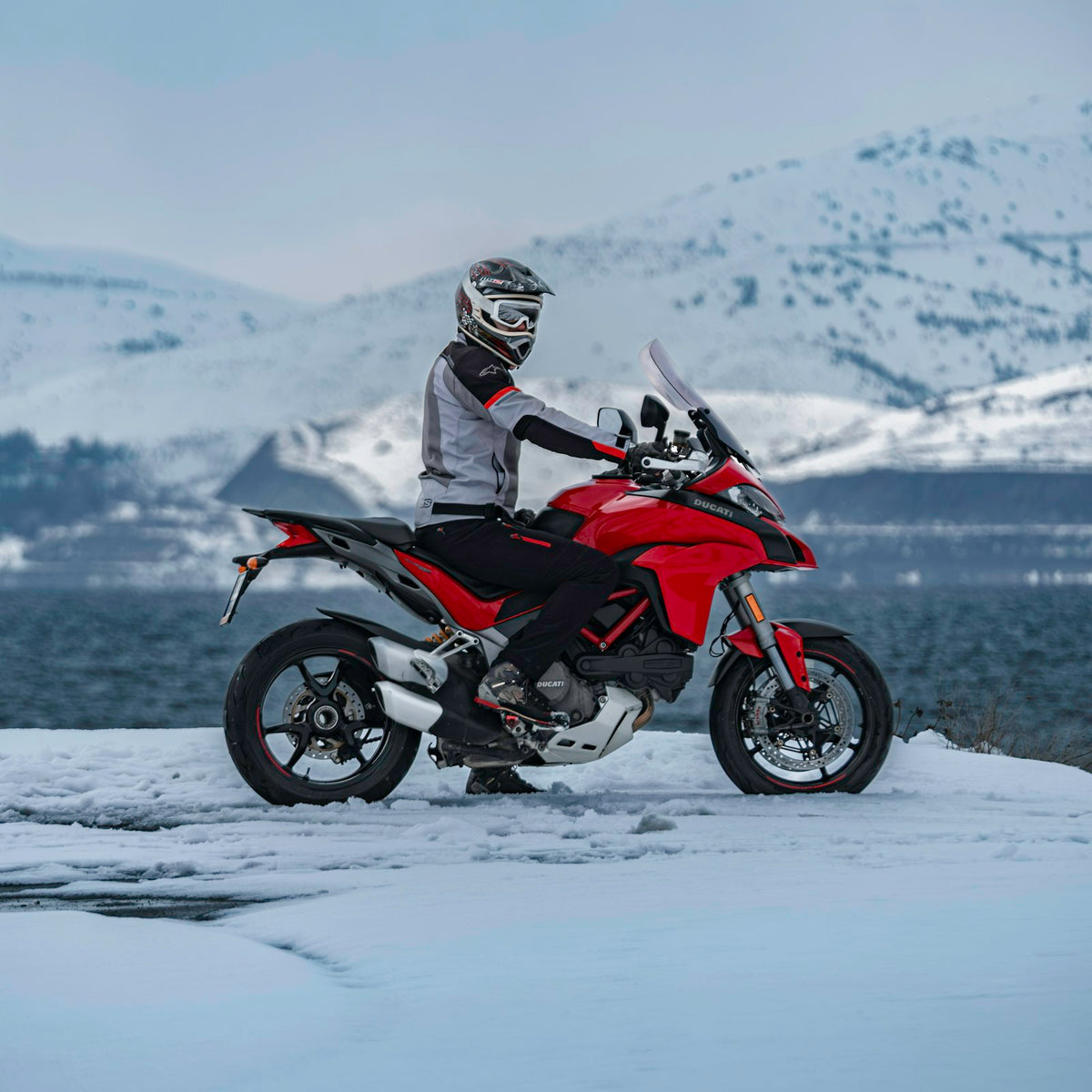 Rider in a winter motorcycle jacket in a snowy landscape