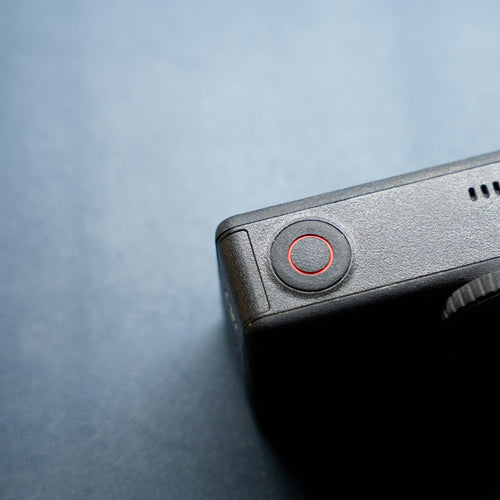 Black action camera with a red button