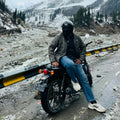 Motorcyclist in a thermal jacket with snowy mountains behind